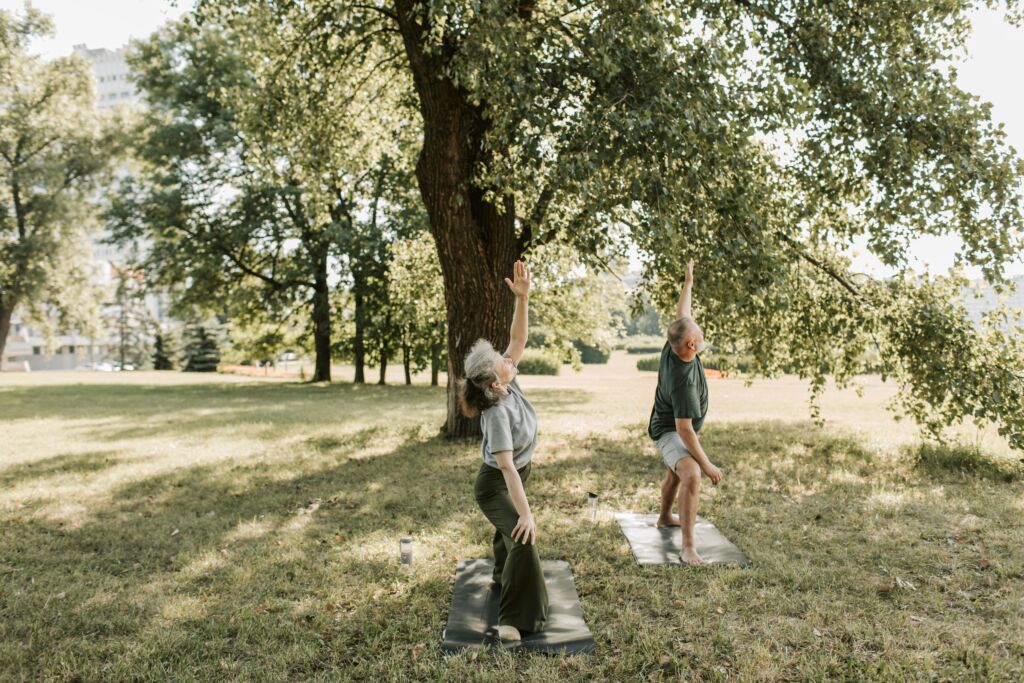Senior couple enjoying yoga practice outdoors, promoting a healthy and active lifestyle.